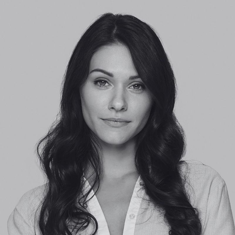 Portrait of a woman with long dark hair and a light blouse, offering a serene and professional appearance.